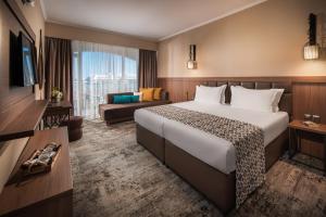 ein Hotelzimmer mit einem großen Bett und einer Couch in der Unterkunft Hotel Alba - All inclusive in Sonnenstrand + 50 Fotos