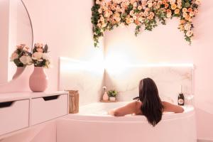 a woman sitting in a bath tub with flowers at Almond Jacuzzi Suites - Private Indoor Jacuzzi - Self Check-In - Free & Easy Street Parking in Thessaloniki