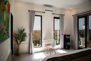a bedroom with two windows and a table and a chair at Parafrutts Apartments by Ateliero in Ubud