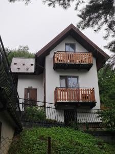 a white house with two balconies and trees at Kwatery u Potoków in Piwniczna-Zdrój