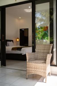 a room with a bed and a wicker chair and a bedroom at Parafrutts Apartments by Ateliero in Ubud