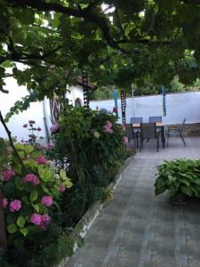 a patio with pink flowers and tables and chairs at Къща Йорданови in Chernomorets