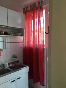 a kitchen with a red shower curtain and a sink at Къща Йорданови in Chernomorets