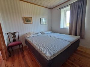 a bedroom with a bed and a chair and a window at Nickarve Gård Hejdeby in Visby