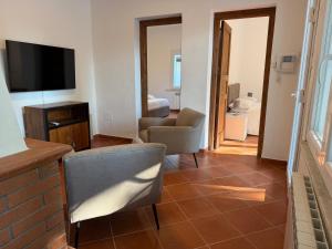 a living room with a television and a couch and a chair at Marinella Retreat - Brezza in Zambrone