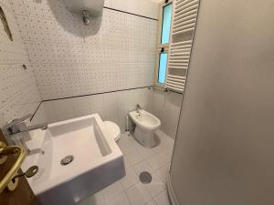 a white bathroom with a sink and a toilet at Marinella Retreat - Brezza in Zambrone
