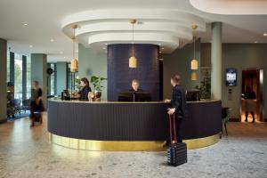 a man with a suitcase standing at a counter in a lobby at Van der Valk Hotel Venlo in Venlo +59 photos