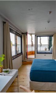 a bedroom with a blue bed and two windows at Dahabiya cruise in Luxor