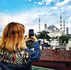 a woman taking a picture of a mosque with her cell phone at Angel's Home Hotel - Angel Group Hotels in Istanbul +84 photos