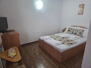 a small bedroom with a bed and a table at La Camuflaj 2 Mai in 2 Mai