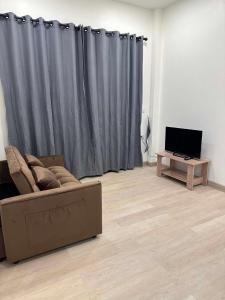a living room with a couch and a table with a television at The Summer Cozy Cottage in Haad Chao Phao