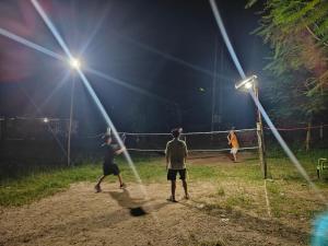 three men playing a game of tennis at night at The Gulmohar Grove in Pāsighāt