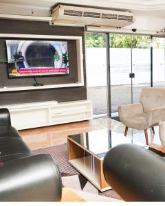 a living room with a flat screen tv and chairs at Hotel Ciudad Nueva in Ciudad del Este