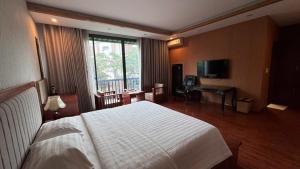 a bedroom with a large white bed and a desk at Sakura building hotel & restaurand in Hải Dương