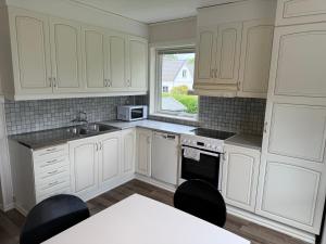 a kitchen with white cabinets and a sink and a table at Hardangegatan in Östersund