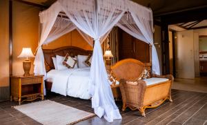 a bedroom with a bed with a canopy and two chairs at Kilima Safari Camp in Amboseli +60 photos