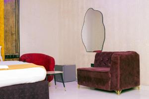 a bedroom with a bed and a chair and a mirror at Indian Atlantic Hotel & Suites in Agbor