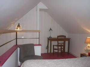 a bedroom with a bed and a table and a chair at L'ânesque in Saint-Augustin-des-Bois
