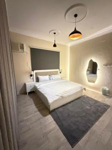 a bedroom with a large white bed and a rug at أوبال ستاي المطار in Abha