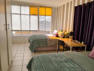 a bedroom with two beds and a table with a desk at Kapokbos in Sutherland