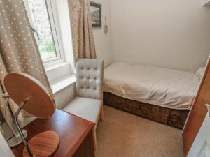 a small bedroom with a bed and a desk and a chair at Kernot Cottage in Richmond