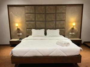 a bedroom with a large white bed with two lights at DK Club & Resort in Bārdoli