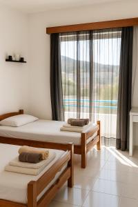 a bedroom with two beds and a large window at Merryland Studios & Apartments in Kremasti