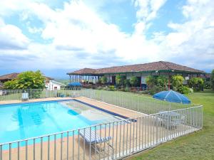 a swimming pool with a fence and a house at Finca Hotel Caracolí I A 15 Minutos del Parque del Café in Montenegro