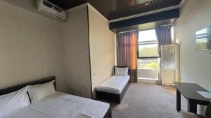 a room with two beds and a desk and a window at Sohil Hotel in Stantsiya Kyzyl-Tukumachi