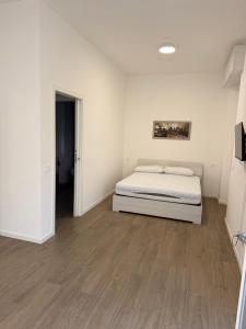 a white bedroom with a bed and wooden floors at Artexia residence DIAMANTE A1 in Valenza