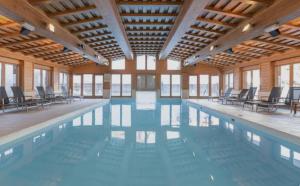 a large swimming pool with chairs in a building at Studio Premium ARC 1950 in Bourg-Saint-Maurice