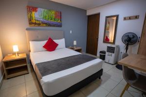 a bedroom with a white bed with red pillows at Aguacatala Hotel Boutique in Medellín