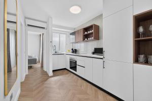 a white kitchen with wooden floors and white cabinets at Coast Suites in Alcalá