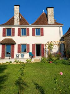 a large white house with red shutters and a yard at Chambre double alcôve in Lagor
