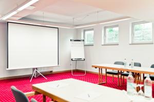 a conference room with tables and a white screen at Schweiger's Landgasthof in Wartenberg