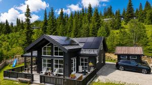 a black house with solar panels on it at Flott utsikt Peis Elbillader in Aurdal