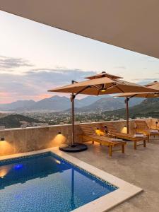 a swimming pool with two umbrellas and benches next to at Villa Beyond Bar in Bar