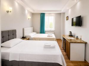 a hotel room with two beds and a television at Mavi OTEL BOUTİQUE RESTAURANT in Mahmutlu