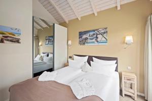a bedroom with a bed with white sheets and a mirror at Luxuswellnesshaus Dünenperle in Bliesdorf