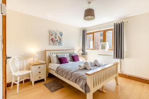 a bedroom with a large bed with purple pillows at 3 Bed in Whitchurch Canonicorum oc-43395 in Whitchurch Canonicorum