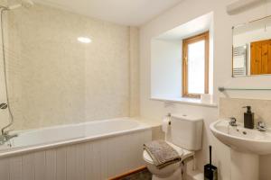 a bathroom with a tub and a toilet and a sink at 3 Bed in Whitchurch Canonicorum oc-43395 in Whitchurch Canonicorum +17 photos