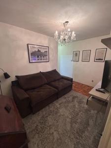 a living room with a brown couch and a chandelier at Lindo Apartamento próximo ao Centro in Juiz de Fora