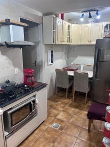 a kitchen with a stove and a table with chairs at Lindo Apartamento próximo ao Centro in Juiz de Fora
