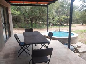 a patio with a table and chairs and a swimming pool at Khoneni in Marloth Park