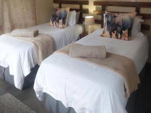 two beds with white sheets with cows on them at Khoneni in Marloth Park +11 photos