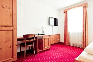 a room with a desk with a chair and a television at Schweiger's Landgasthof in Wartenberg