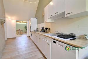 a kitchen with white cabinets and a wooden floor at La grée des dinosaures in Saint-Gravé
