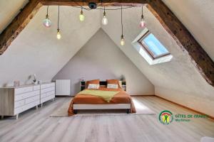 a bedroom in an attic with a bed and a window at La grée des dinosaures in Saint-Gravé