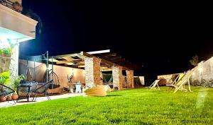 a backyard at night with a grass yard at Къщата в Ахелой in Aheloy