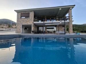 a house with a swimming pool in front of a house at Το ραχατι in Vília